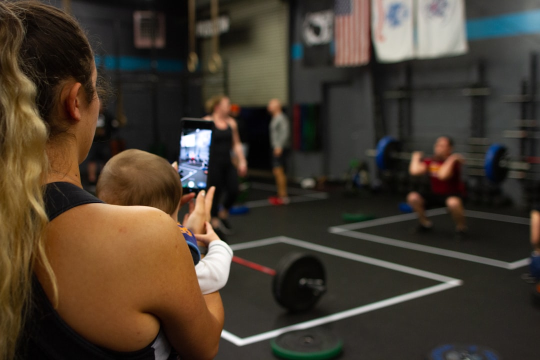 Person logging a deadlift workout on their phone in a gym setting