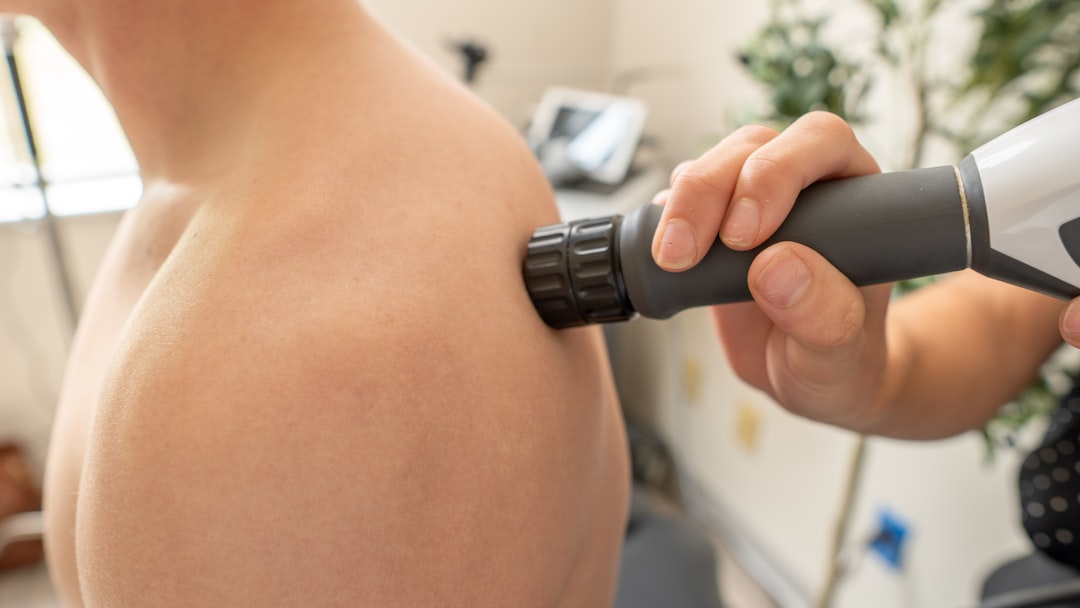 athlete using percussion massage gun on shoulder muscle post-workout