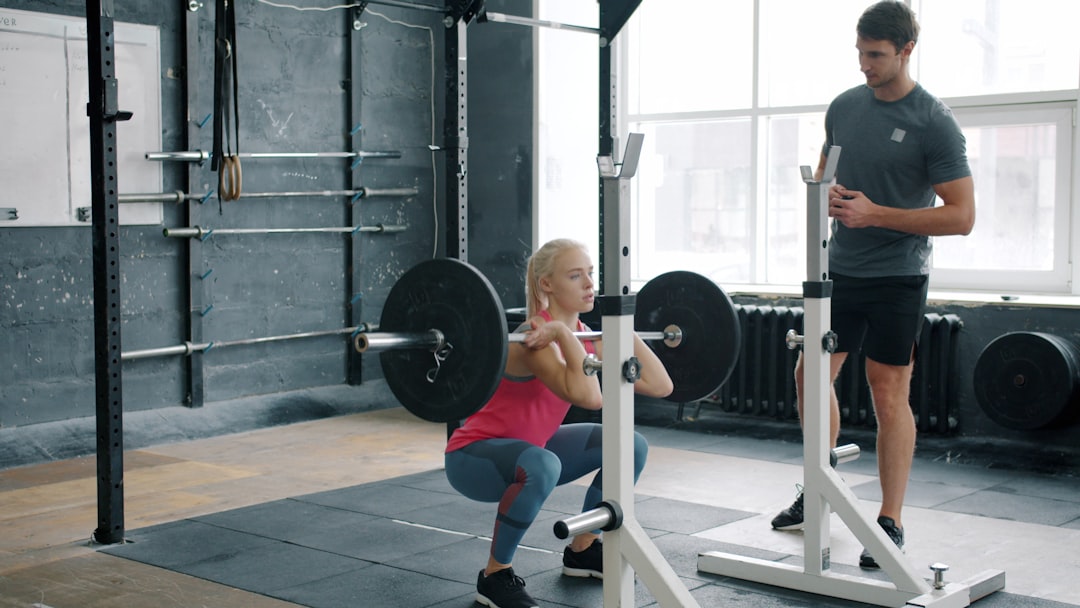 person logging workout on phone at gym squat rack