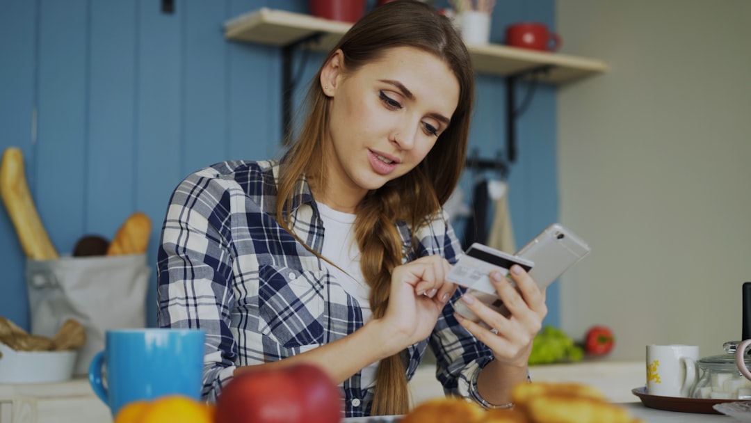person using smartphone food diary app at kitchen table with groceries