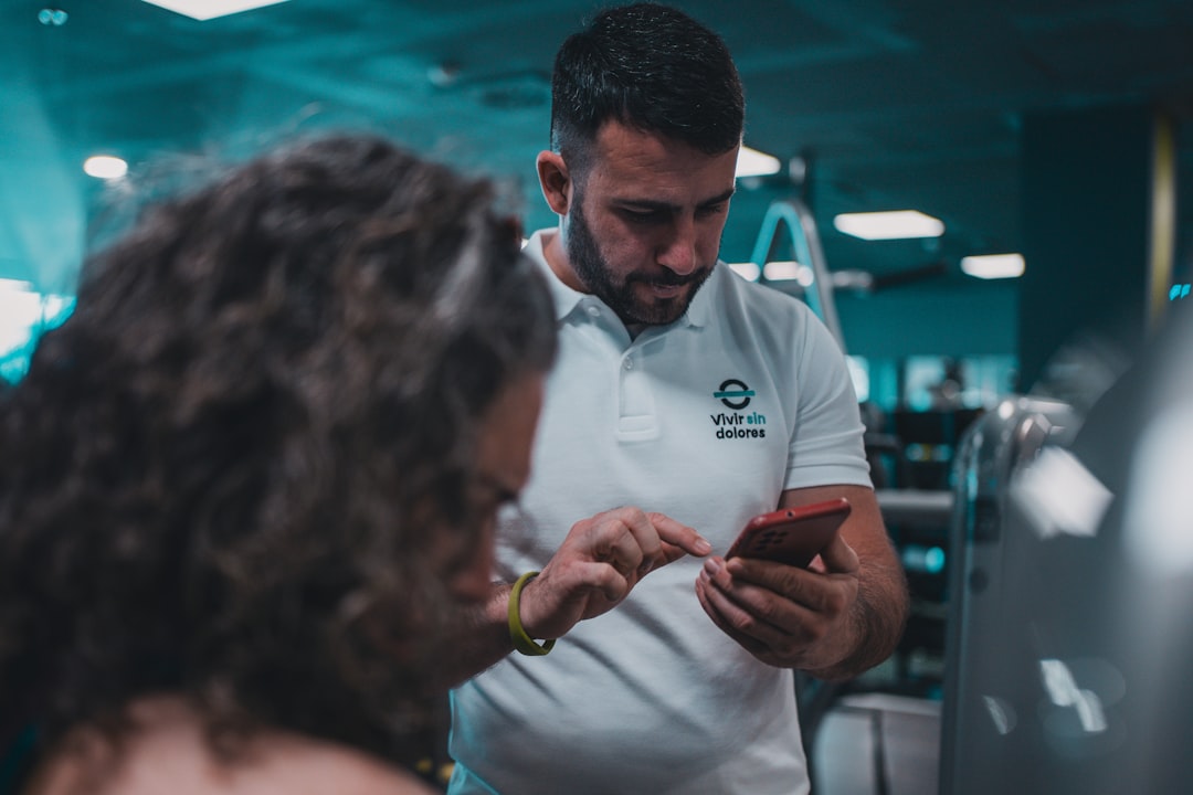 personal trainer using fitness coaching app on smartphone with client