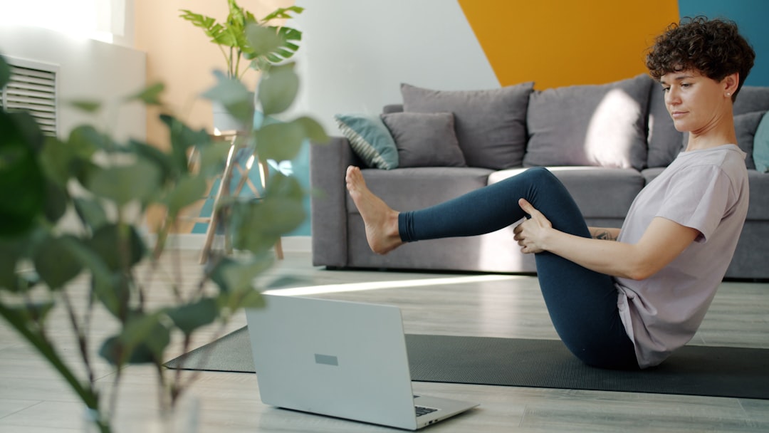 person doing bodyweight workout at home using laptop for guidance