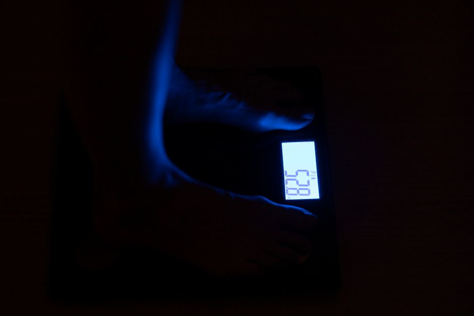 Person stepping on Renpho scale in modern bathroom with phone displaying health metrics