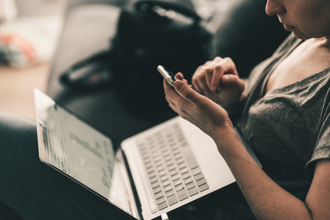 personal trainer using fitness coaching software on laptop and phone