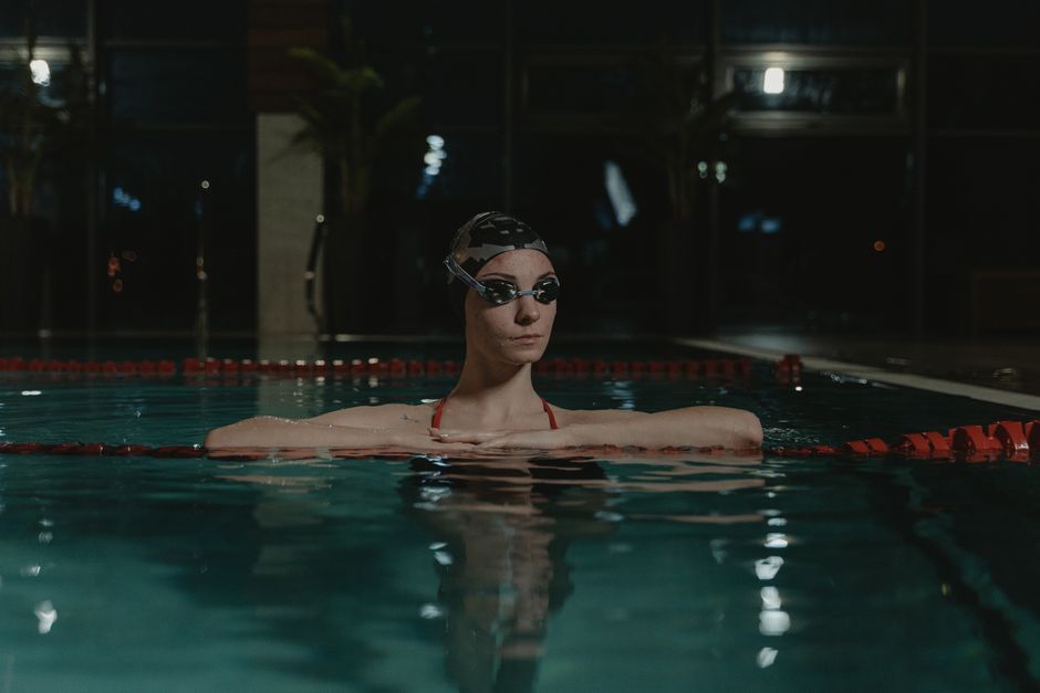 swimmer wearing FORM goggles reviewing workout data on smartphone poolside