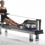 Person in rowing position on a WaterRower Metallic rowing machine, silver aluminium frame